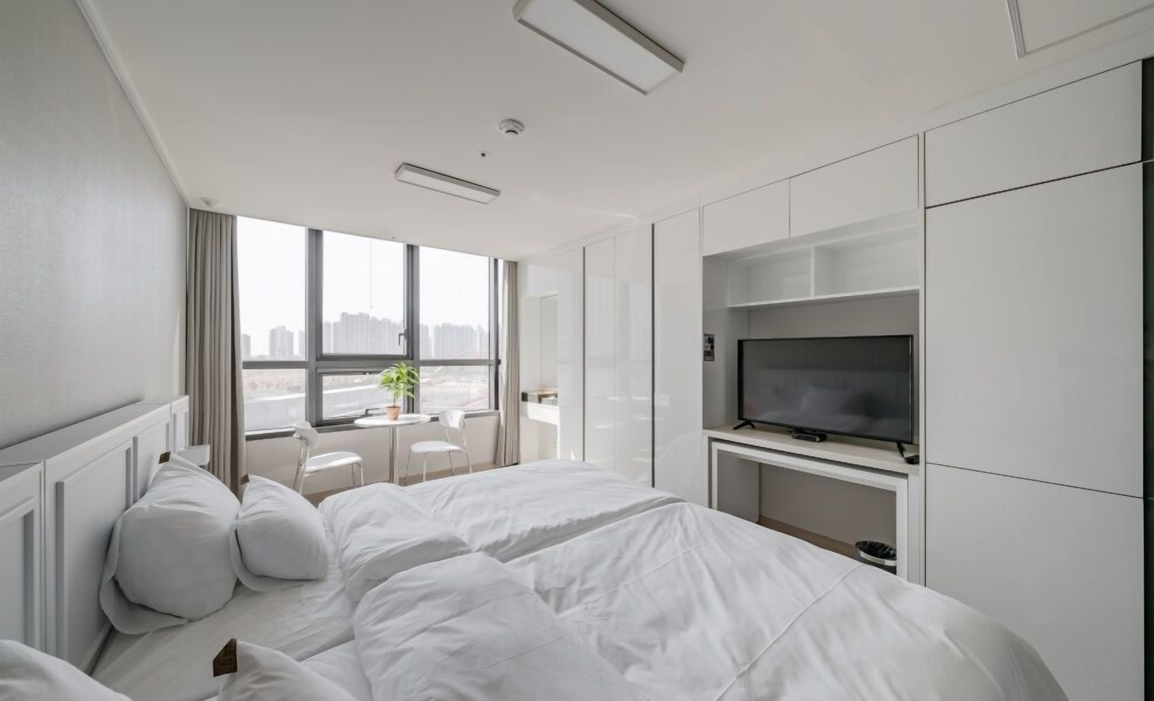 A modern hotel room with a large bed, a TV, and a city view.