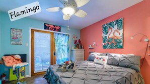 A bedroom with a bed, a ceiling fan, a door, and a window with blinds.