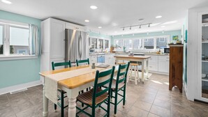 Una cocina moderna con armarios blancos, una mesa de comedor de madera y sillas verdes.