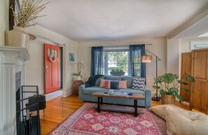 Sala de estar com sofá, mesa de centro e uma porta vermelha.
