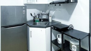A compact kitchen with a refrigerator, a sink, and a microwave. - Room-warm Urban Studio With Modern Desig (Iloilo)