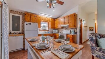 A kitchen with wooden cabinets, a central island with dining setup, and a ceiling fan.