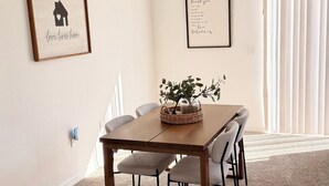 Un coin repas avec une table en bois, des chaises et un tableau encadré au mur.