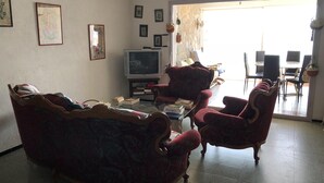 A living room with a sofa, armchairs, a coffee table, and a television. - Apartment in Roses in first sea line (Roses)