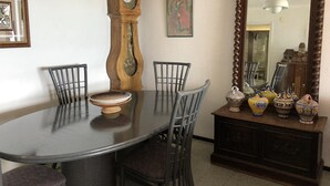 A dining area with a round table, four chairs, a wooden clock, a mirror, and decorative vases. - Apartment in Roses in first sea line (Roses)