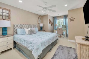 A bedroom with a bed, nightstands, a desk, a chair, a ceiling fan, and a star decoration on the wall. - Relax and Unwind in Sunny St. Simons! Private Pool + Outdoor Oasis! (St. Simons Island)