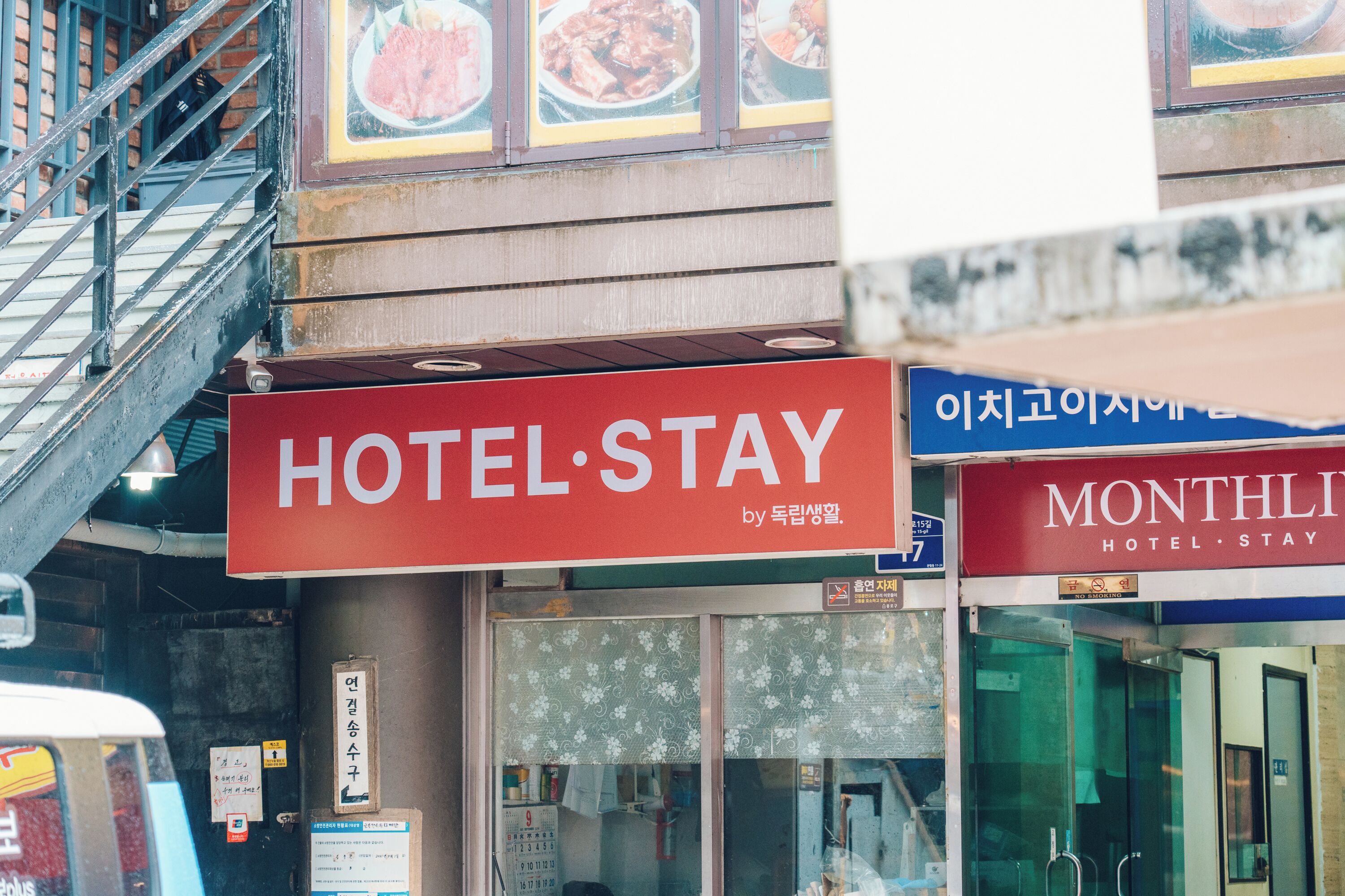 A hotel named HOTEL STAY with a red sign and a glass door entrance.