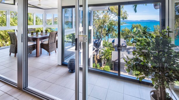 Zona pranzo moderna con una porta in vetro che dà su un balcone con vista panoramica sull'oceano.
