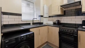 A compact kitchen with a washing machine, a stove, and a sink. - Discounted stay for long stays and contractors in the heart of Greenwich (London)
