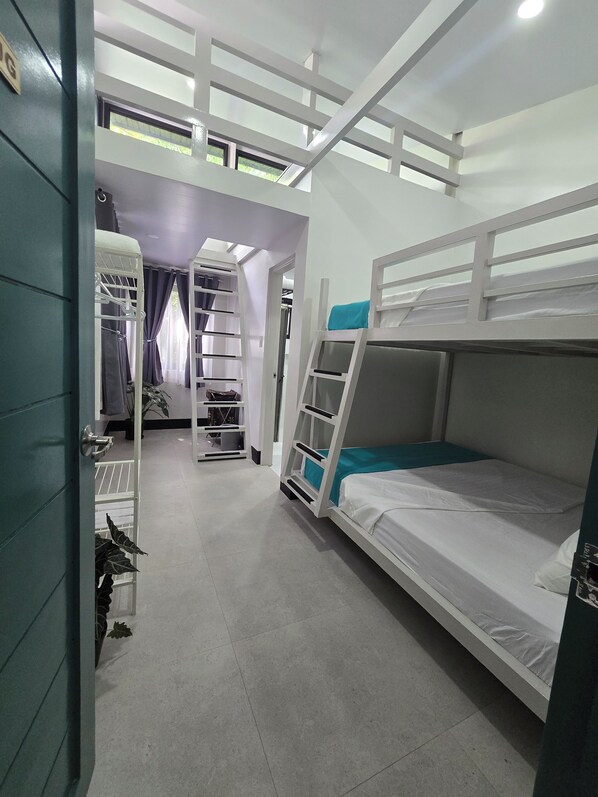Un dormitorio con literas, un armario y una escalera que lleva a un nivel superior.