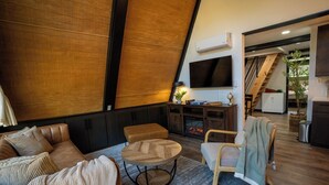 A modern living room with leather sofas, a wooden coffee table, and a TV mounted on the wall. - Golf Lovers 2-bedroom A-Frame Cabin by Big Cedar Golf (Omaha)