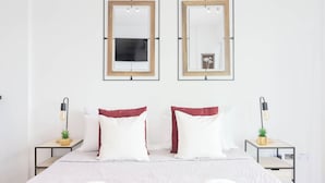 A hotel room with a bed, two nightstands, two wall-mounted mirrors, and a small potted plant on each nightstand.