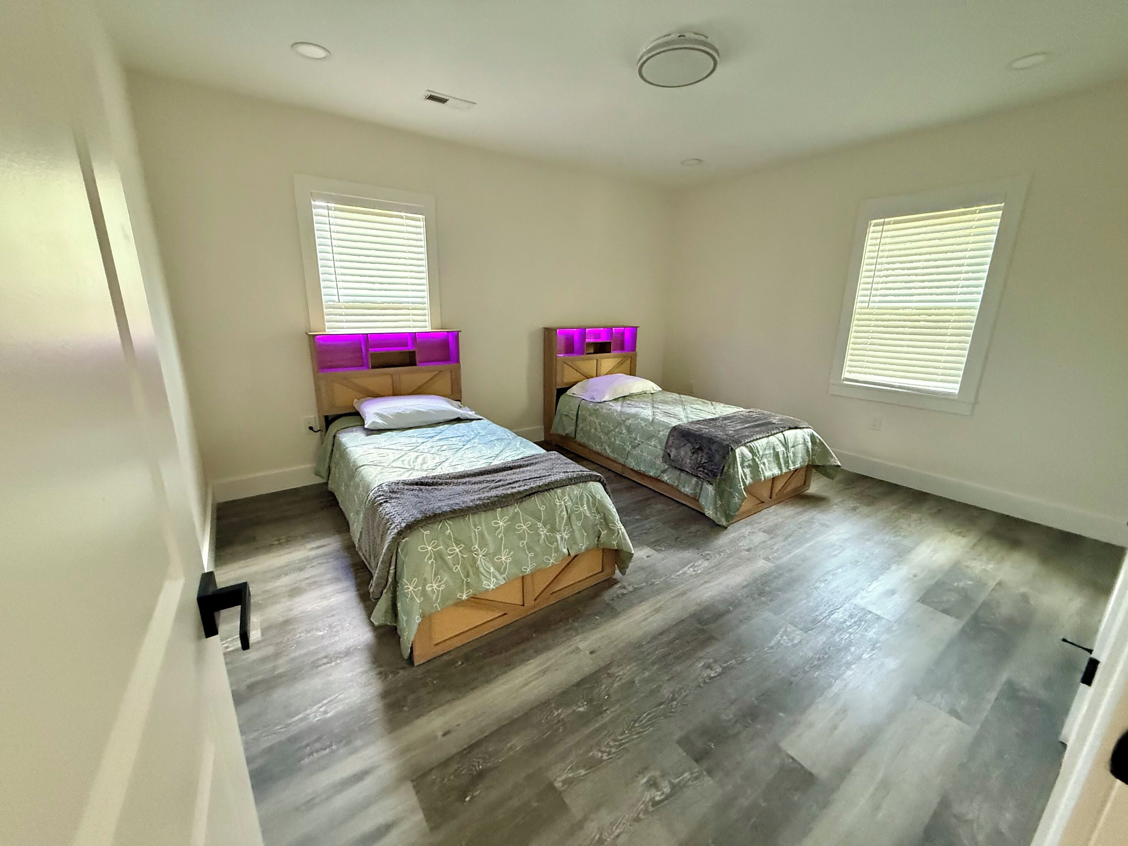 Habitación con dos camas, cabeceros de madera y una ventana con persianas.