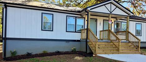 A single-story mobile home with a front porch and a set of wooden stairs leading to the entrance.