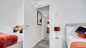 Habitación de hotel con dos camas, una mesita de noche, una lámpara y una puerta que da al baño.