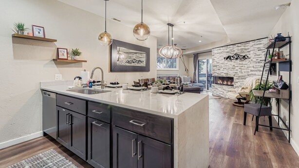 A modern kitchen with a central island, pendant lights, and a stone accent wall. - Peaceful Lift Line Condo 207 3 Bedroom Condo (Park City)