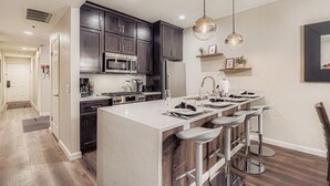 A modern kitchen with dark cabinets, stainless steel appliances, and a large island with bar stools. - Peaceful Lift Line Condo 207 3 Bedroom Condo (Park City)