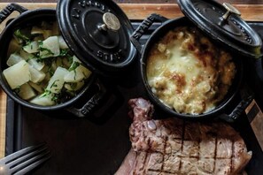 Un repas composé de deux plats et d’un steak grillé.