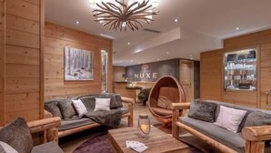 A cozy interior with wooden walls, a NUXE sign, and a round wooden chair. - Hotel la Chaudanne (Meribel)