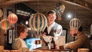 A bar area with hanging hot air balloons, a bartender, and a customer. - Hotel la Chaudanne (Meribel)