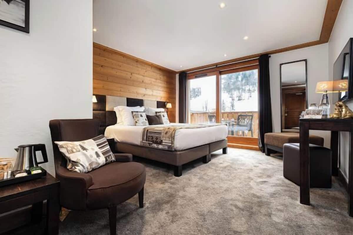 Un dormitorio con cama, una silla, un escritorio y un ventanal grande.