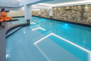 Une piscine intérieure aux murs en pierre, avec un jouet en peluche sur le côté gauche.