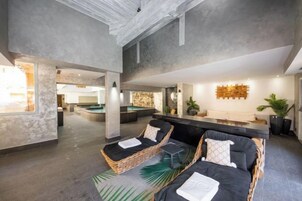 Un vaste espace intérieur comprenant une piscine, un coin salon et un comptoir d’accueil.