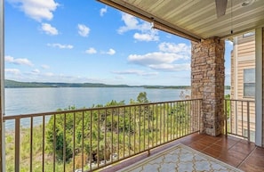 Un balcon avec un pilier en pierre, une vue sur un lac et une balustrade.