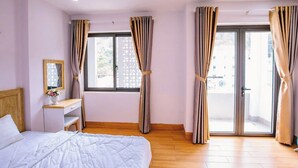 Een slaapkamer met een bed, een nachtkastje, een spiegel en een raam met gordijnen.