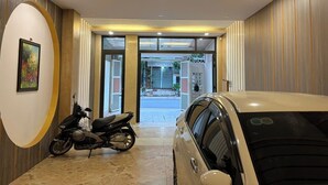 Een moderne hotelentree met een motor en een auto ervoor geparkeerd.