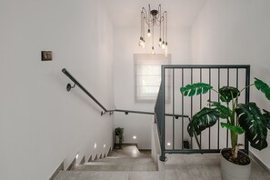 A staircase with a metal railing, a potted plant, and a hanging light fixture.