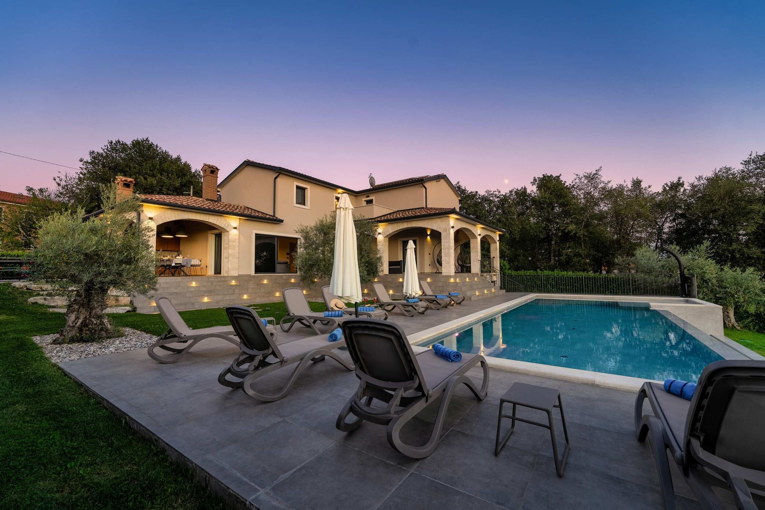 A residential property with a swimming pool, outdoor seating, and a landscaped garden.