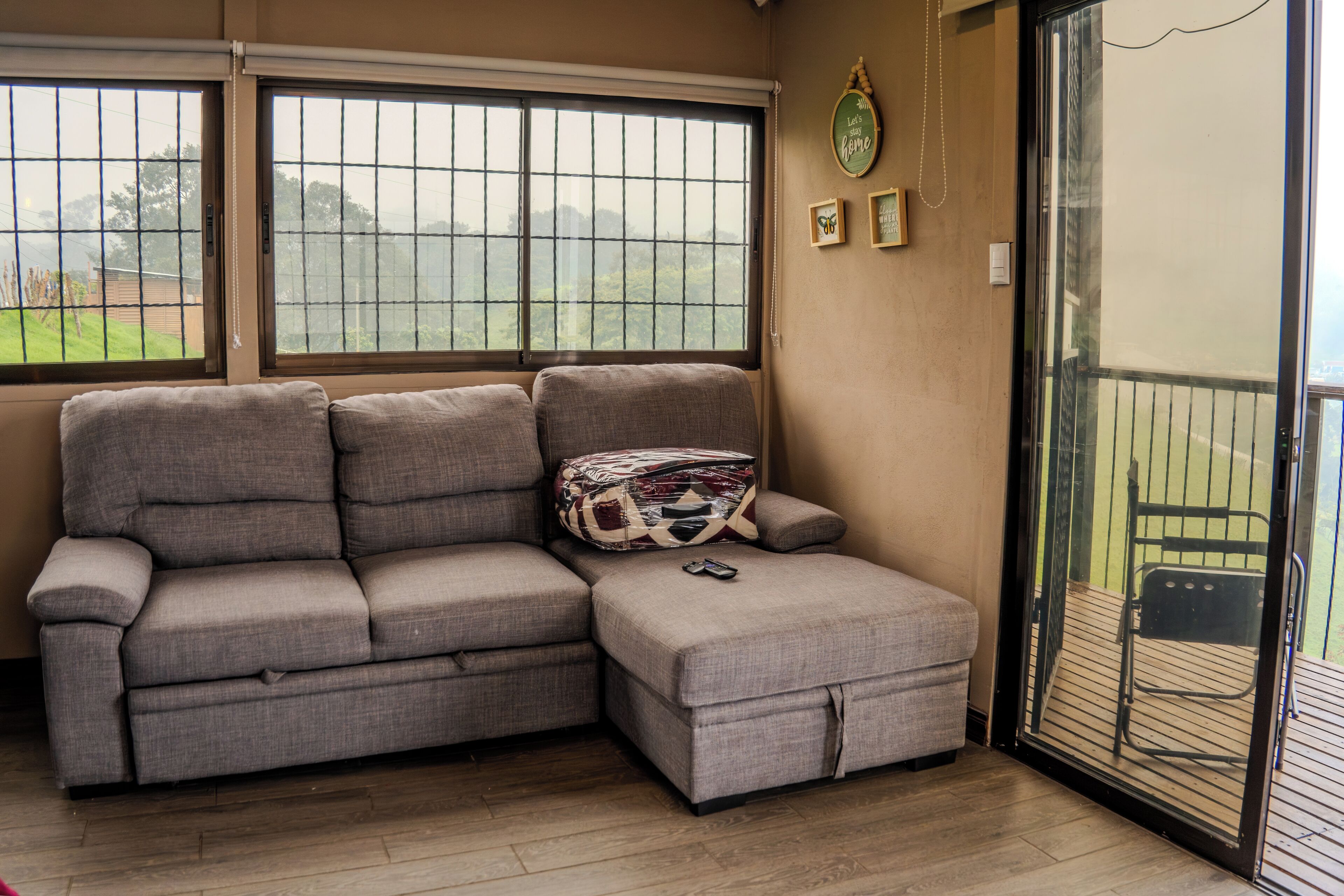 A sectional sofa with a matching ottoman, a patterned throw pillow, and a remote control on the ottoman.