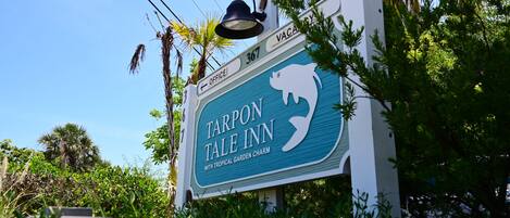 En skylt för Tarpon Tale Inn, med en tropisk trädgård som ger platsen en speciell charm.