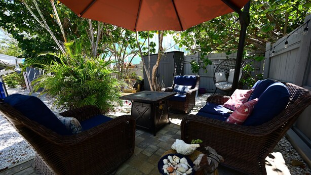 A patio area with wicker furniture, a table, and a bowl of snacks.