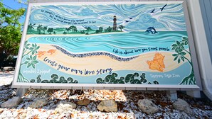 A beach-themed signboard with inspirational quotes and the name 'Tarpon Tale Inn'.