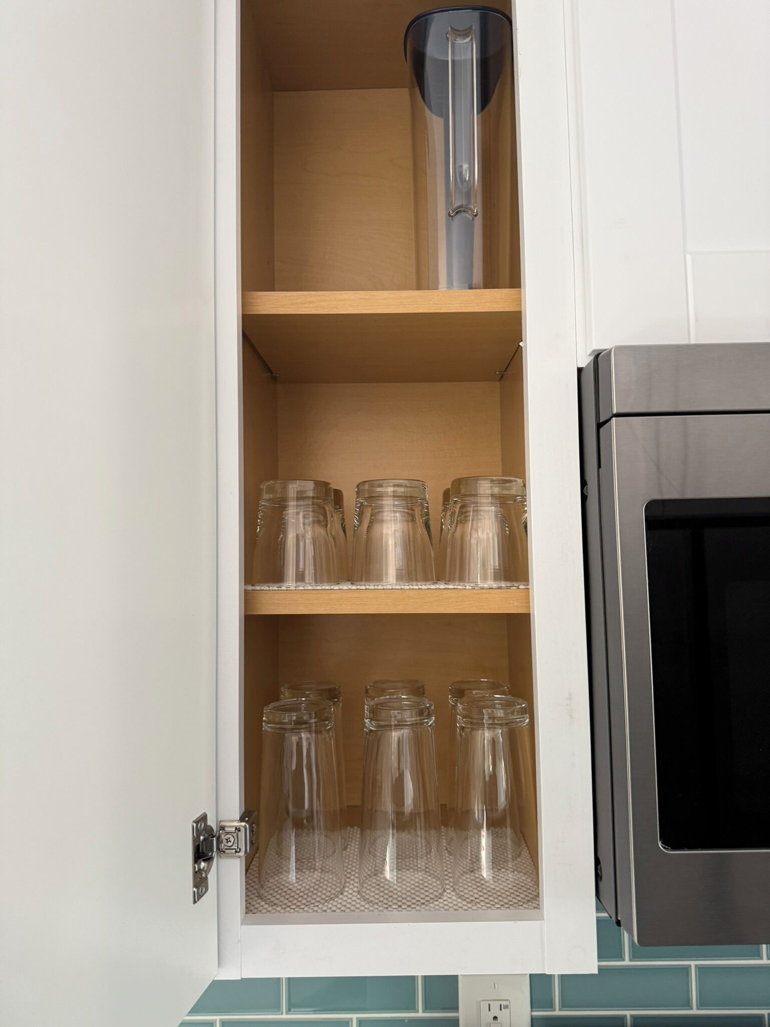 Ett köksskåp med tre hyllor, där varje hylla innehåller genomskinliga glasburkar.