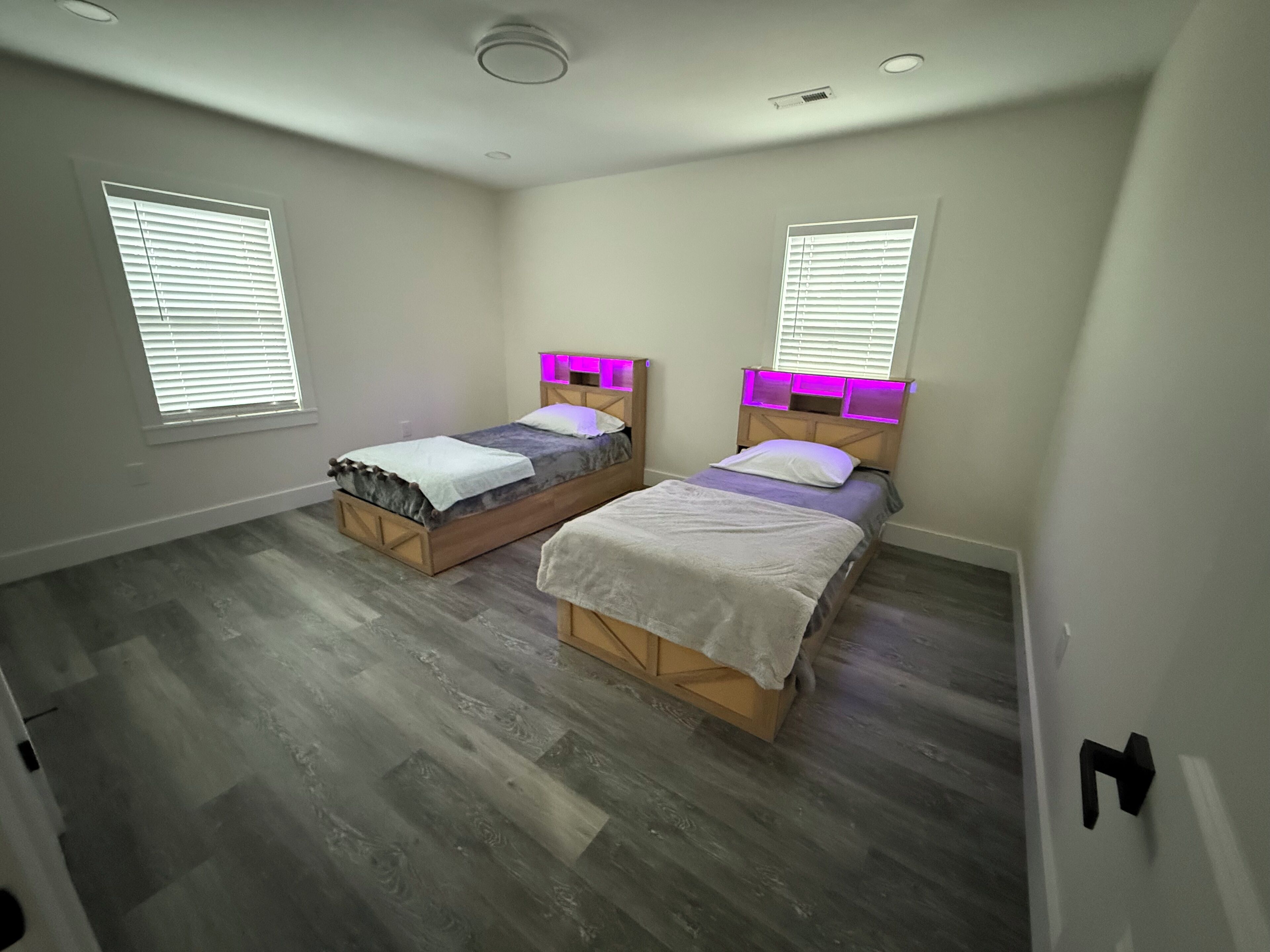 A bedroom with two beds, wooden headboards, and built-in lighting.
