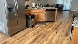 Une cuisine moderne avec des meubles en bois, un réfrigérateur en acier inoxydable, un lave-vaisselle et un plan de travail en granit.