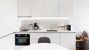 Een moderne keuken met witte kastjes, een ingebouwde oven, een koffiezetapparaat en een spoelbak.