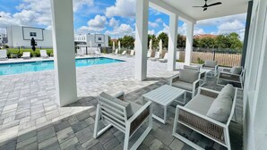 A covered outdoor area with a pool, lounge chairs, and a ceiling fan.