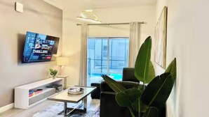 A modern living room with a flat-screen TV, a coffee table, a sofa, and a large plant.
