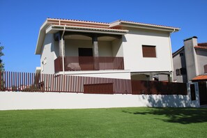 Un bâtiment à deux étages doté d’un balcon, d’une façade blanche et d’un toit recouvert de tuiles rouges.
