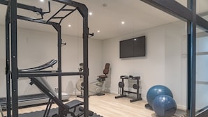 A gym with exercise equipment, a wall-mounted TV, and a wooden floor. - ma-la studios Guimarães 304 (Guimarães)
