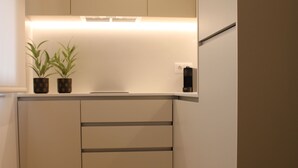 A modern kitchen with wooden cabinets, a countertop, and two potted plants. - ma-la studios Guimarães 304 (Guimarães)