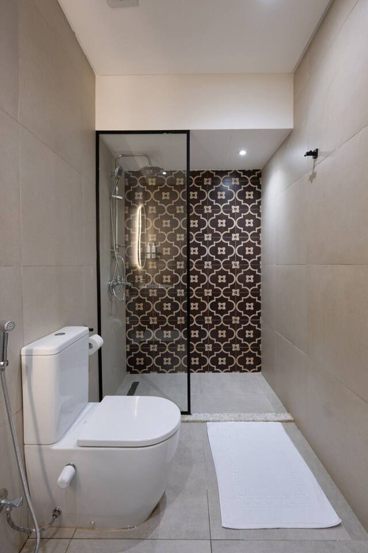 Une salle de bain moderne avec des toilettes, une douche et des carreaux à motifs.