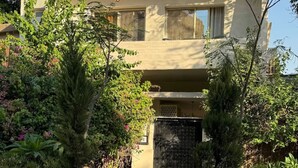 Un immeuble de deux étages avec une façade beige, de grandes fenêtres et une entrée fermée par un portail.