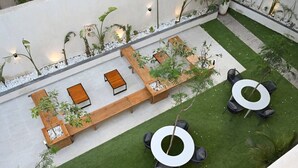 Un jardin sur le toit, aménagé avec des espaces pour s’asseoir, des jardinières et un petit élément décoratif aquatique.