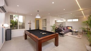 Un salon moderne avec une table de billard, un ensemble de canapés et une grande fenêtre.