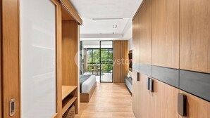 A modern hotel room with wooden cabinetry, a bed with a view, and a balcony. - Levora by Kozystay - Nusa Dua (Nusa Dua)